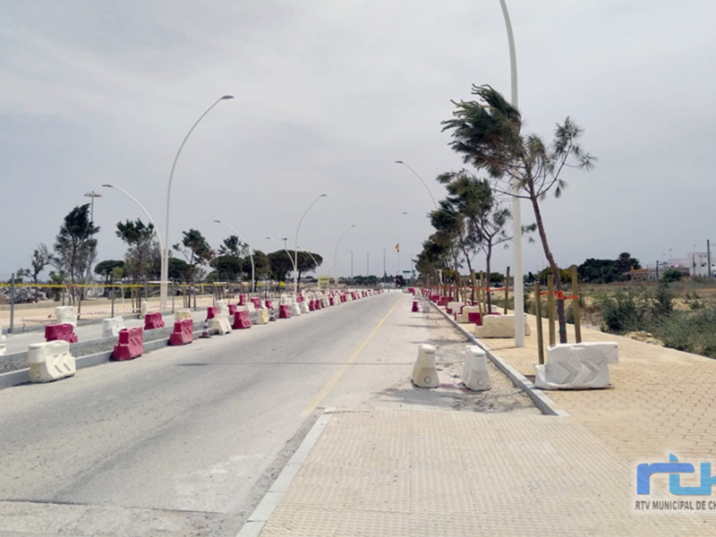 Vista de una carretera con barreras de seguridad y árboles en el lado derecho, bajo un cielo nublado.
