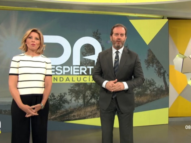 Presentadores en un estudio de televisión con fondo de diseño geométrico y logo de 'Despierta Andalucía'.