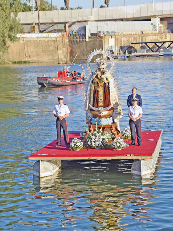 Bote de la Guardia Civil con una imagen religiosa flotando en el agua, acompañado de oficiales de la Guardia Civil.