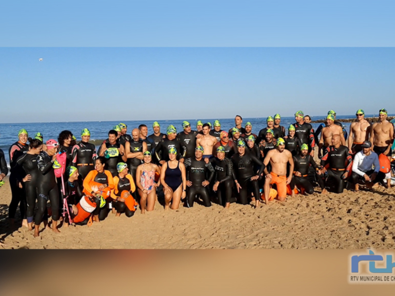 Gente en trajes de natación posando en la playa con el mar y el cielo azul de fondo.