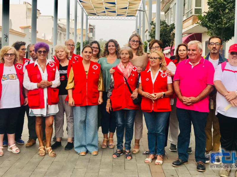 Voluntarios de Cruz Roja posan juntos en una plaza urbana.
