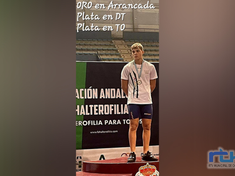 Atleta en el podio ganador de plata en competencia de levantamiento de pesas.