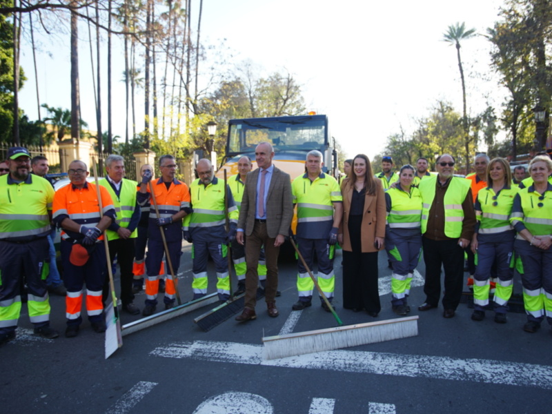 Equipo de limpieza urbana y autoridades posan juntos en una calle con limpiadoras de calles y un vehículo de limpieza.