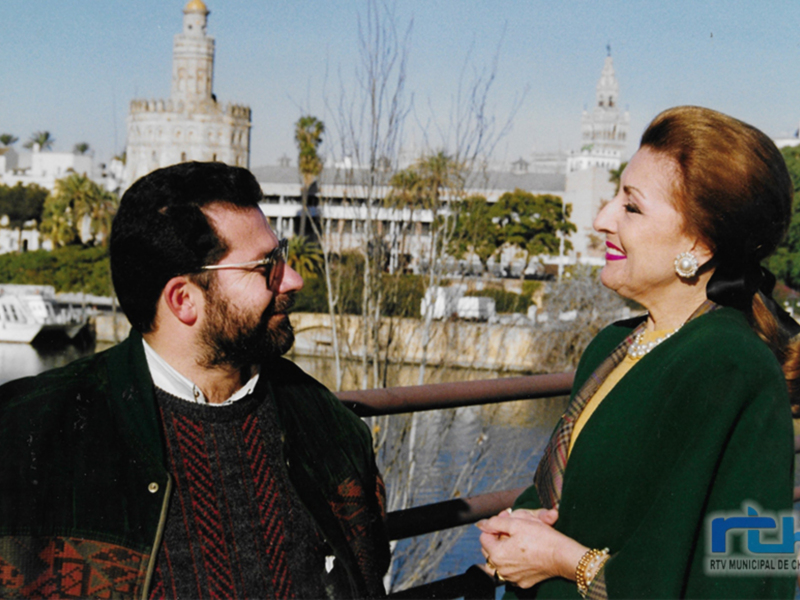 Una pareja conversa en un puente con vistas a la Torre del Oro y el río Guadalquivir en Sevilla, España.