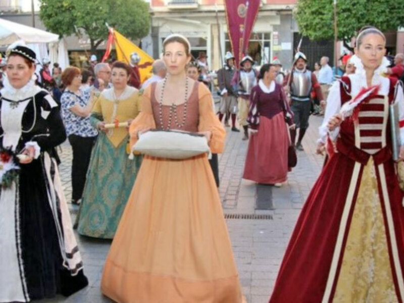 Participantes en trajes medievales caminando en una procesión o festival histórico.