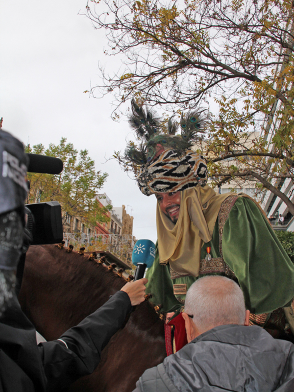 Entrevista a un personaje vestido con traje tradicional y plumas, en un evento al aire libre.