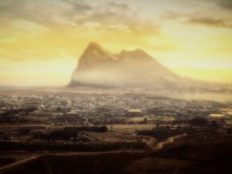 Vista panorámica de una ciudad con montaña en el horizonte bajo un cielo amaneciendo.