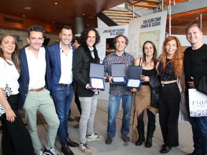 Ganadores de un premio en un evento formal, celebrando con diplomas en mano.