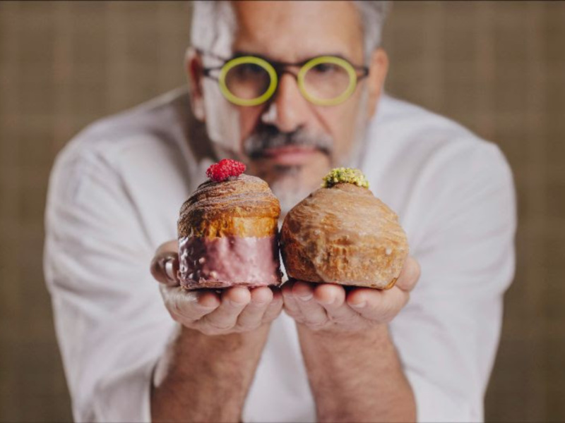 Chef presenta dos deliciosos pastelitos con frambuesa y pistacho, destacando su textura y color.