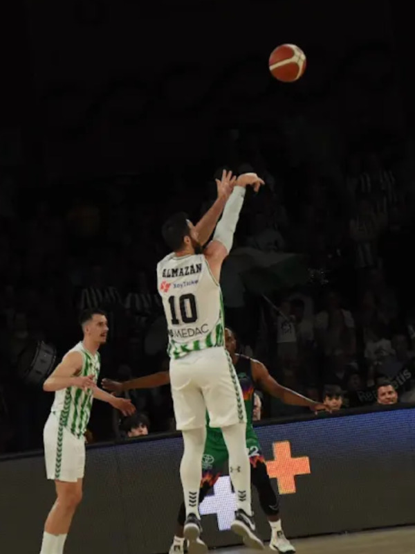 Jugador en el aire intentando marcar durante un partido de baloncesto.