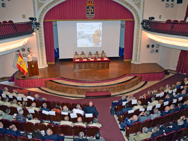 Conferencia en un auditorio con proyección de un cartel y público asistente.