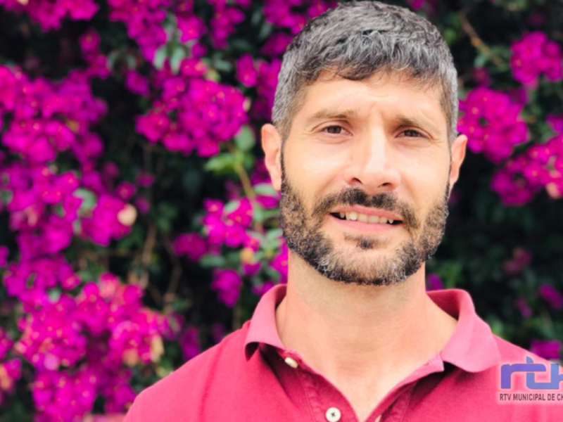 Retrato de hombre sonriente con fondo de flores violetas