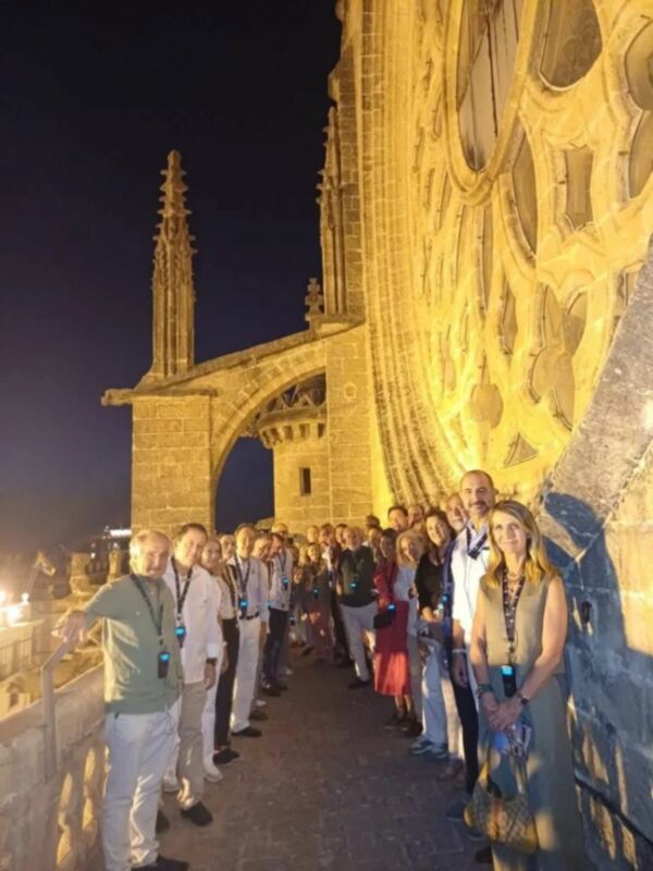 Gente de pie en un puente histórico al atardecer, disfrutando del paisaje nocturno.