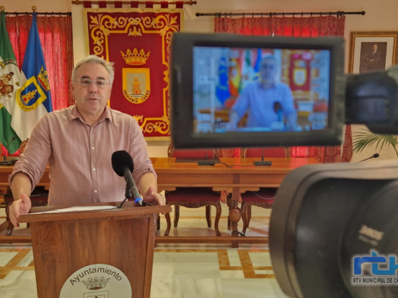 Conferencia de prensa en el Ayuntamiento de Chipiona, con un representante municipal hablando en el escenario.