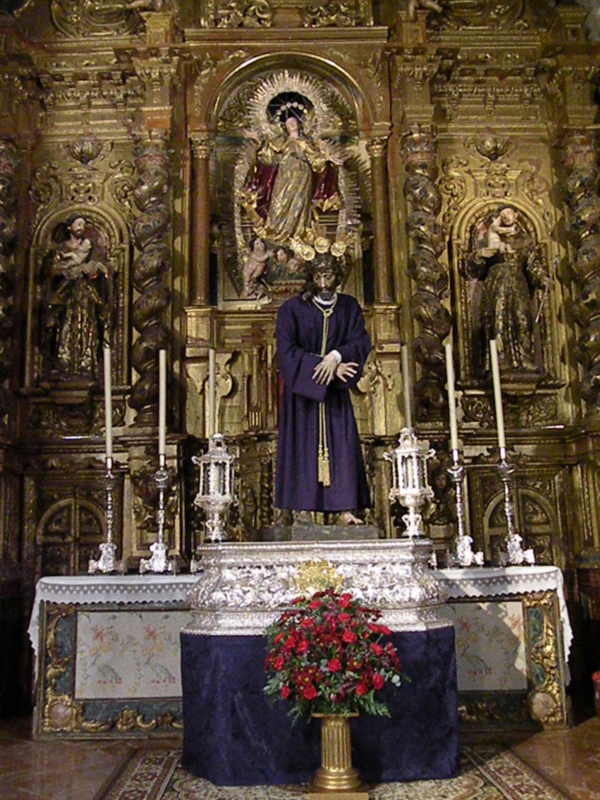 Altar con estatuas y flores en un ambiente religioso.