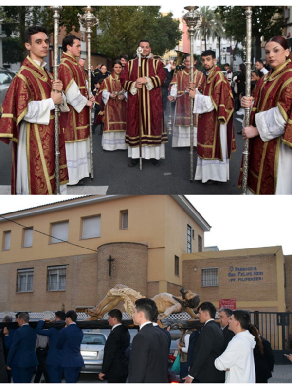 Procesión religiosa con sacerdotes y cofrades portando estandartes en una calle urbana. Edificio de la Parroquia San Felipe Neri en el fondo.