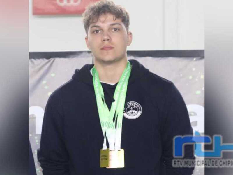 Joven con medalla de oro en el cuello, posando en un evento deportivo.