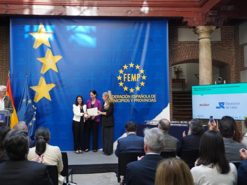 Una ceremonia de premiación en el escenario principal con una bandera europea y un letrero que dice 'FEMP - Federación Española de Municipios y Provincias'.