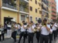 Músicos tocando instrumentos de viento en una calle con edificios de colores.