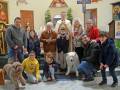 Fotografía familiar en una iglesia con un sacerdote, niños y adultos posando junto a perros.