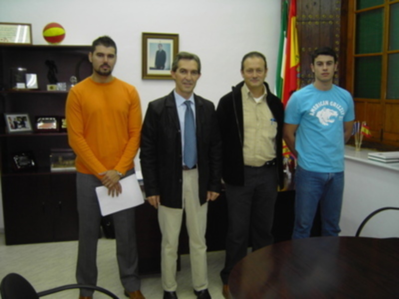 Reunión formal en una oficina, cuatro personas posando juntas.