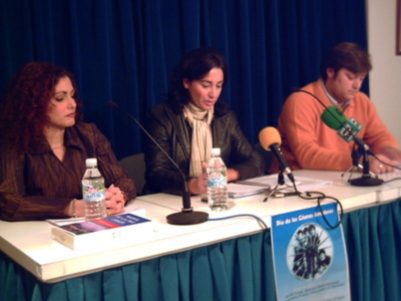 Tres personas participando en una mesa de discusión o presentación en un evento público.