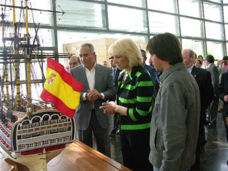 Visita a un museo marítimo, con una réplica de un barco y una bandera española en primer plano.