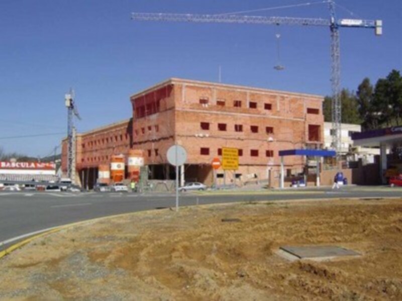 Construcción de un edificio de ladrillo rojo con grúa y obras en curso en un entorno urbano.