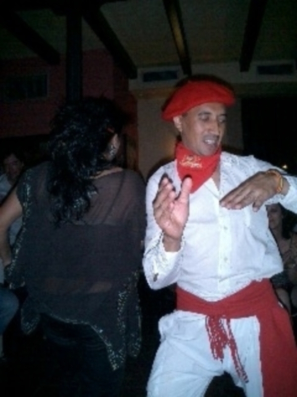 Baile tradicional con vestimenta típica, ambiente festivo y movimiento en un espacio cerrado.