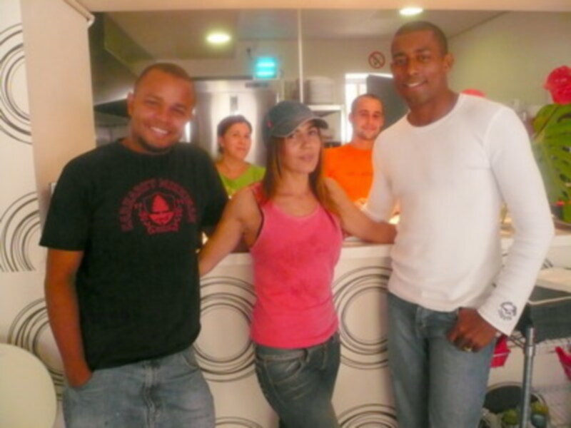 Cuatro personas sonrientes posando juntas en un interior moderno.