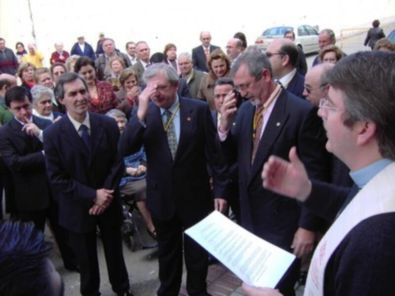 Grupo de personas en una reunión o evento público, con un hombre hablando y otros escuchando atentamente.
