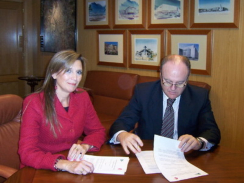 Dos personas firmando documentos en una oficina formal.
