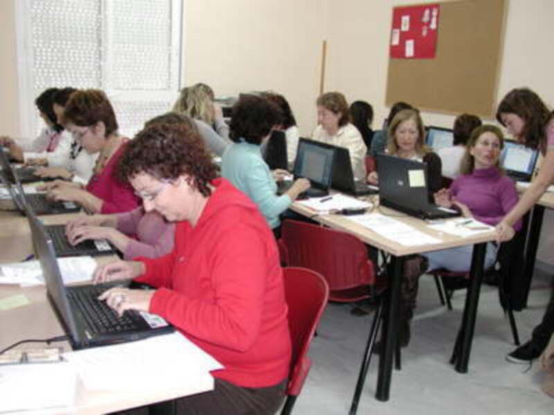Estudiantes en una clase de informática, trabajando con sus computadoras portátiles.