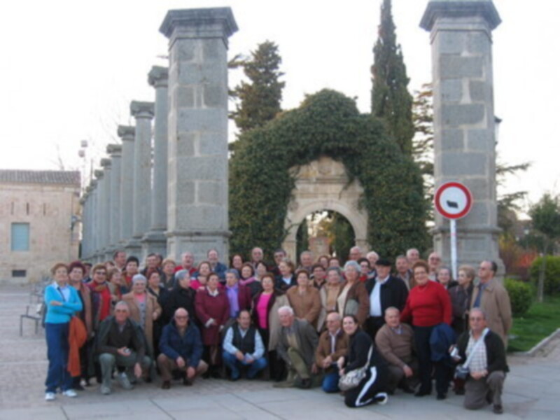 Grupo de personas posando frente a un arco monumental con columnas y una placa.