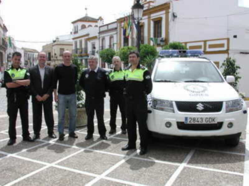 Grupo de policías locales frente a una furgoneta de la Policía Local, en un entorno urbano con edificios típicos.
