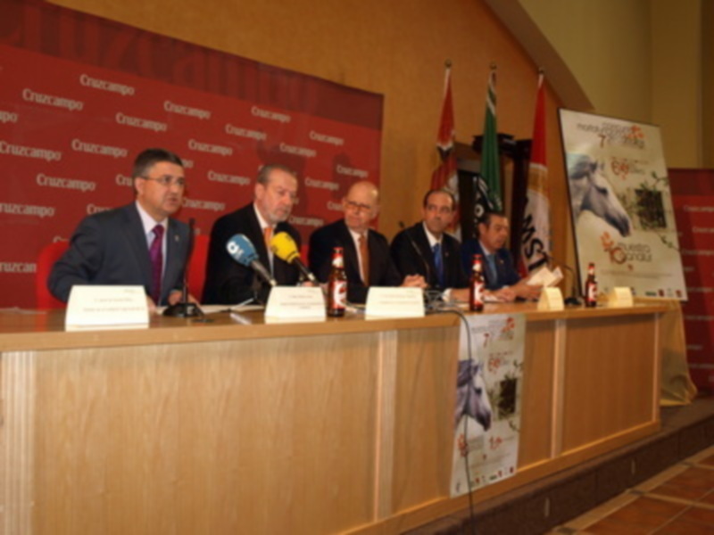 Conferencia de prensa con representantes de empresas en una sala decorada con banderas y carteles promocionales.