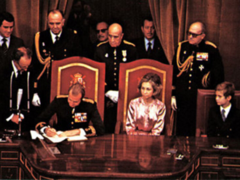 Una reunión formal entre militares y civiles en un entorno ceremonial, posiblemente una ceremonia de firma o acuerdo.