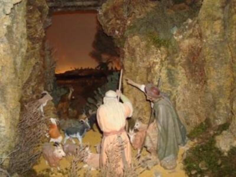 Representación escénica de la natividad con figuras en una cueva y animales alrededor.