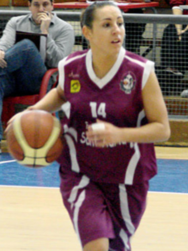 Una jugadora de baloncesto con un uniforme rojo y blanco, posiblemente del equipo "San Antonio", preparándose para un tiro libre en el campo de baloncesto.