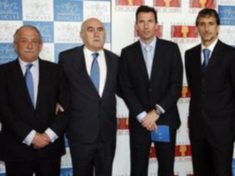Cuatro hombres en trajes formales posando juntos en un evento oficial.