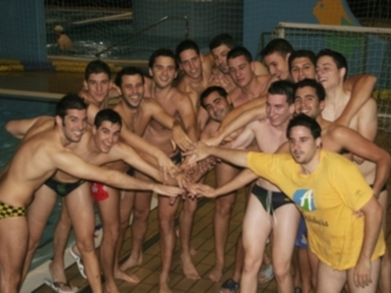 Un grupo de jóvenes nadadores se reúnen en una piscina, con algunos de ellos haciendo un gesto de apoyo alrededor del centro. El ambiente es vibrante y deportivo, reflejando la camaradería entre los participantes.