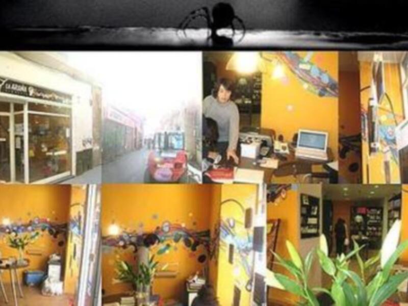 Interior de un café con decoración colorida y moderna, mostrando mesas, sillas y una atmósfera acogedora.