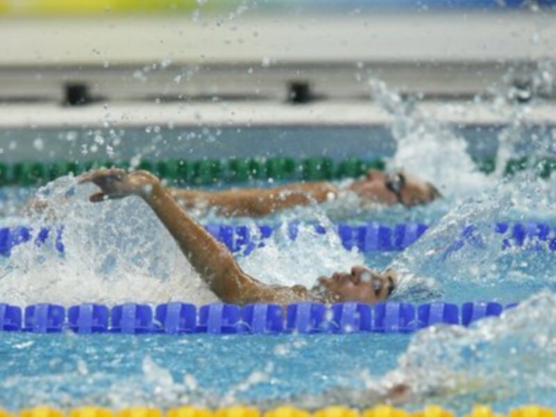 Competidores en una carrera de natación en piscina al aire libre.