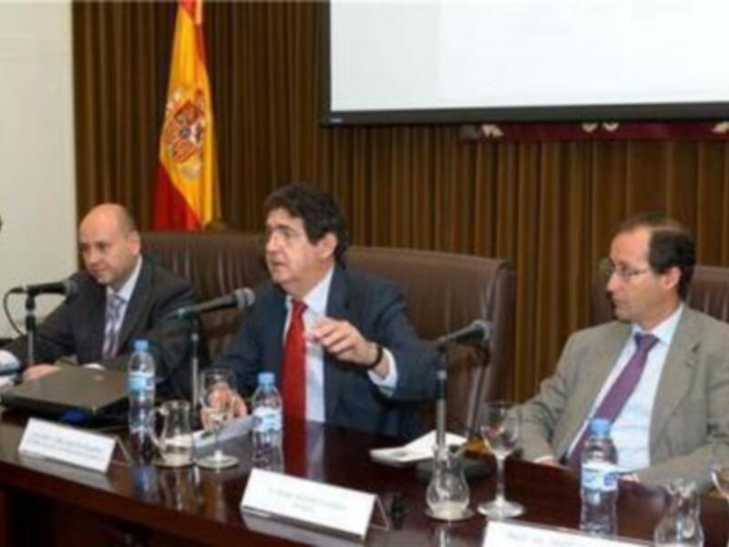 Reunión oficial en un entorno formal con banderas y presentación en pantalla.