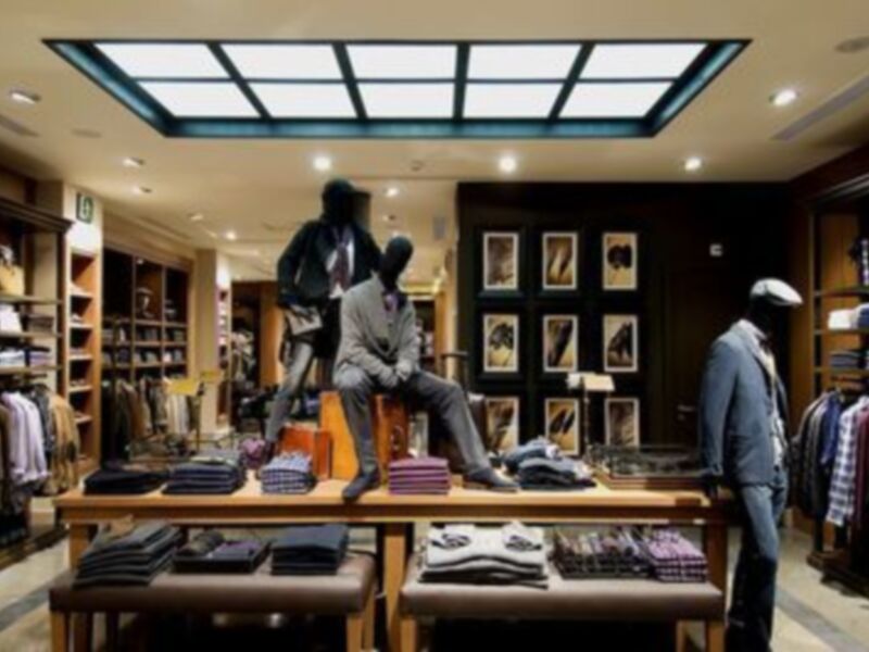 Tienda de ropa con maniquíes vestidos con trajes y camisas, mostrando una colección formal y elegante.