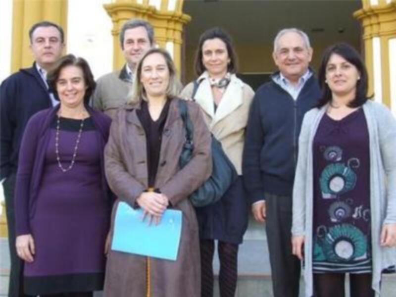 Grupo de personas posando juntos en un entorno urbano, con edificios de estilo clásico al fondo.