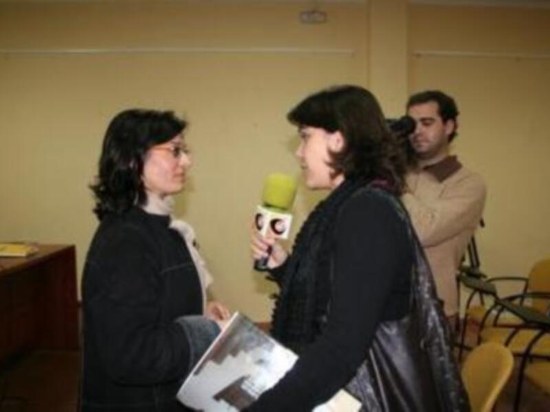 Entrevista en una conferencia o evento profesional, con dos mujeres intercambiando ideas en un ambiente formal.