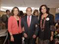 Tres personas sonrientes posando juntas en un evento formal.