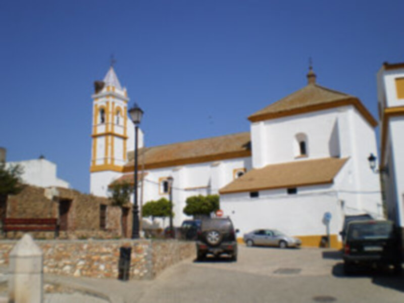 Vista de una iglesia blanca con campanario en un pueblo mediterráneo soleado.