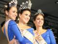 Tres mujeres vestidas con trajes azules y coronas, sonriendo frente a la cámara.